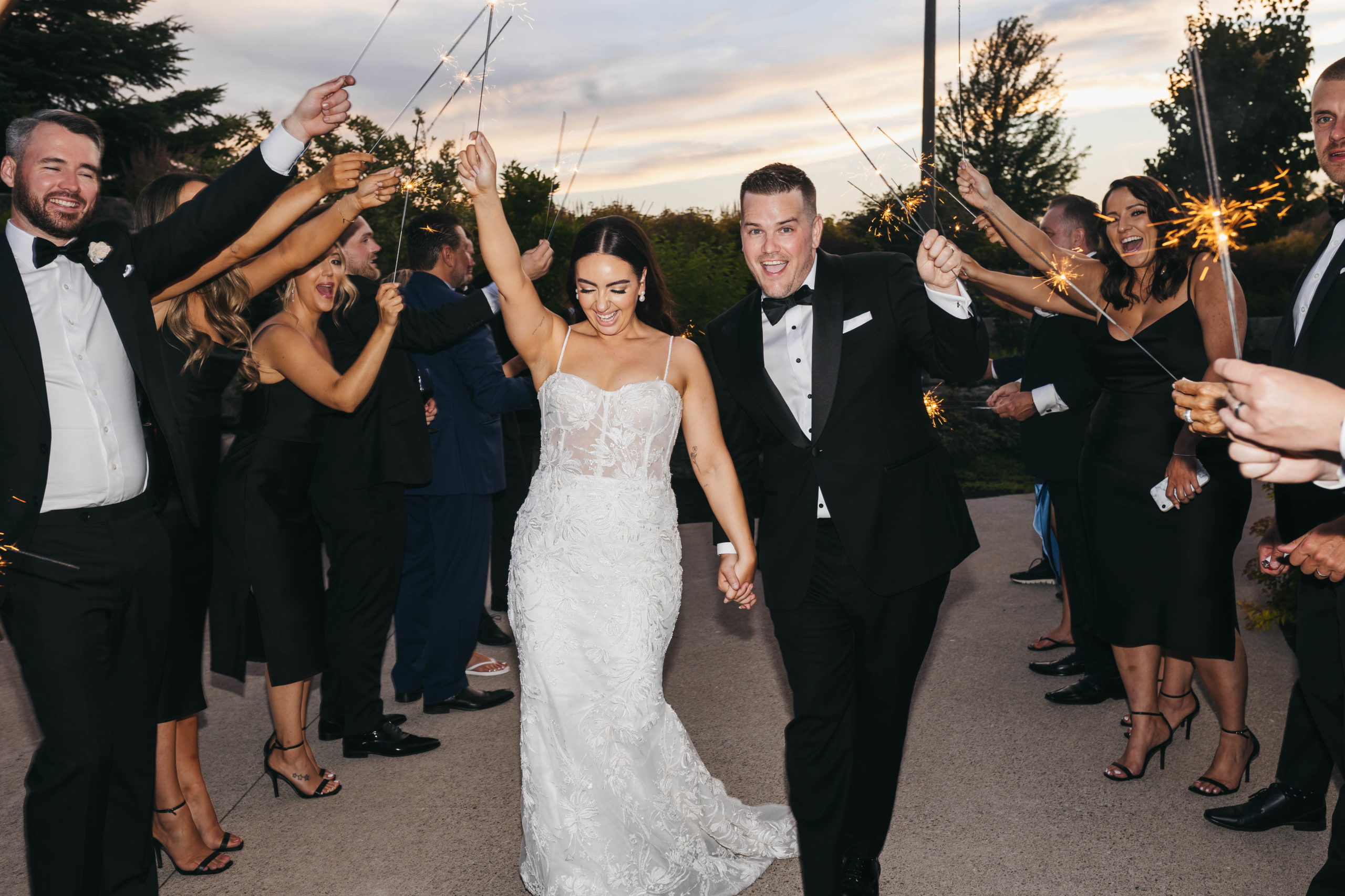 Bride and groom cheers during their walk down a sparkler exit