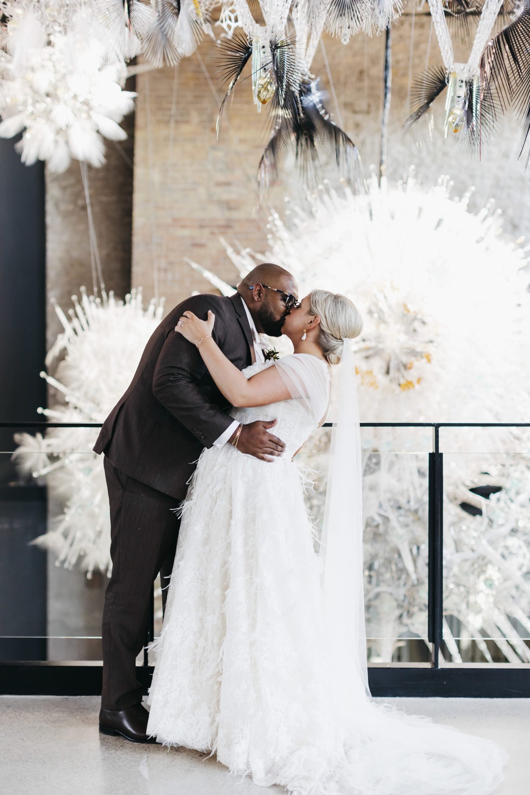 Bride and groom dip kissing in front of giant sparkly hanging installment